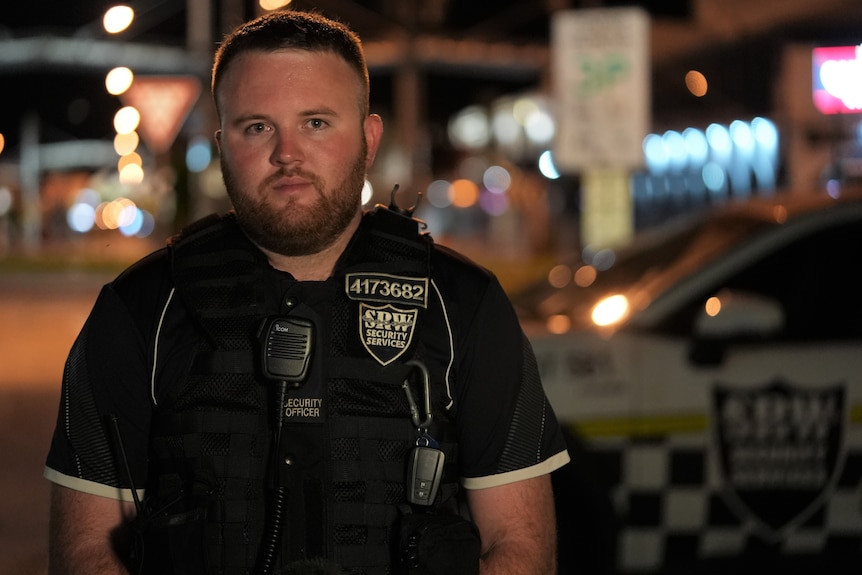 Scott Worlein wears a black and white security guard uniform.