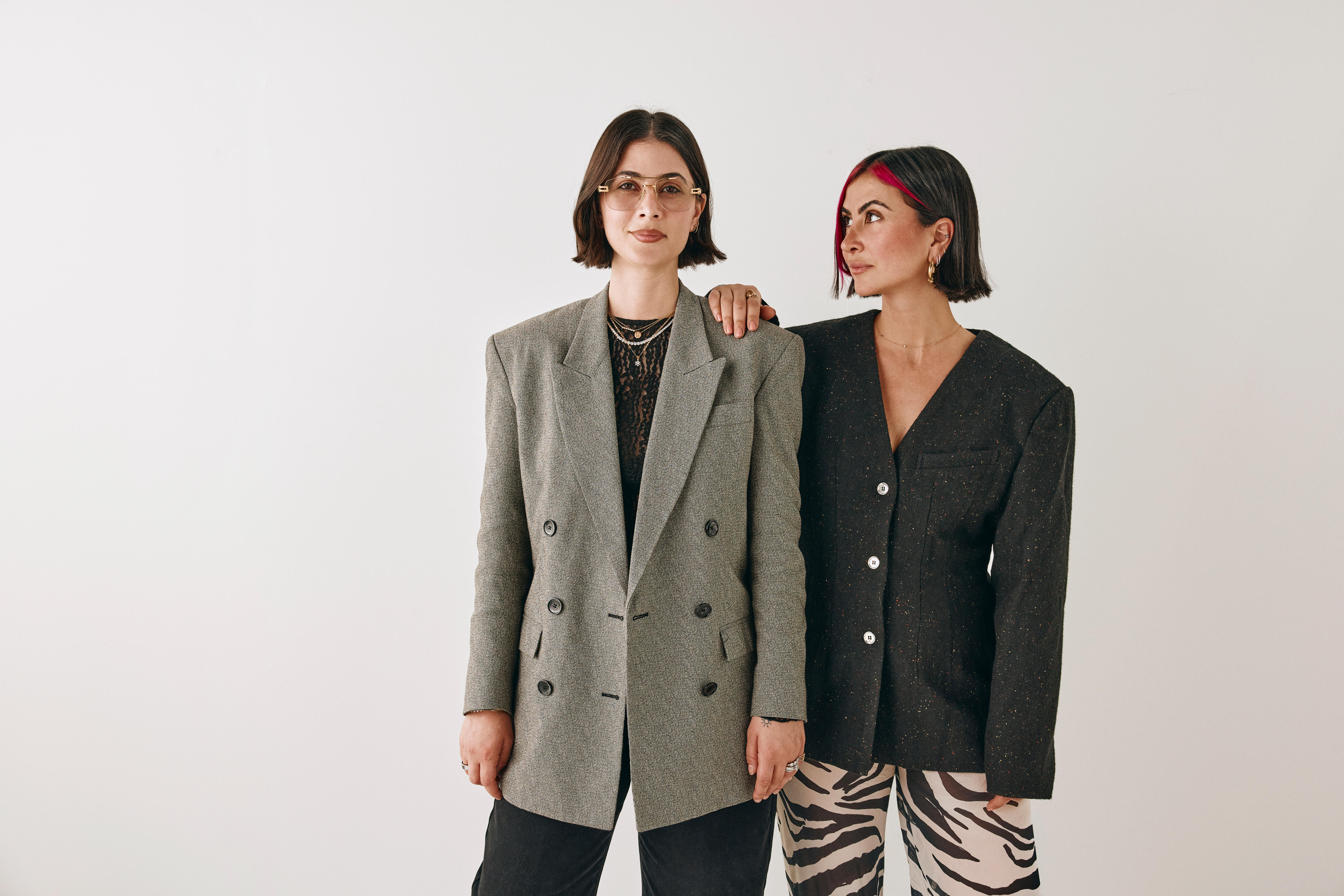 A pair of dark-haired women in fashionable attire.