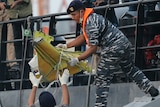Navy personnel carry a recovered part of the Lion Air jet onto a ship.