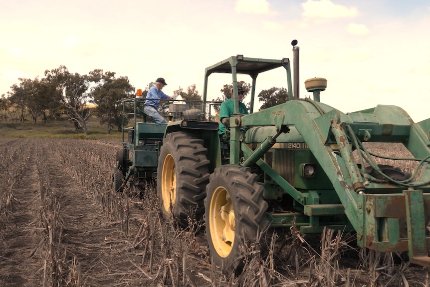 A tractor pulling a seed planter in a paddock