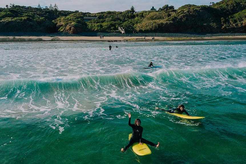 People sit on their surfboards.