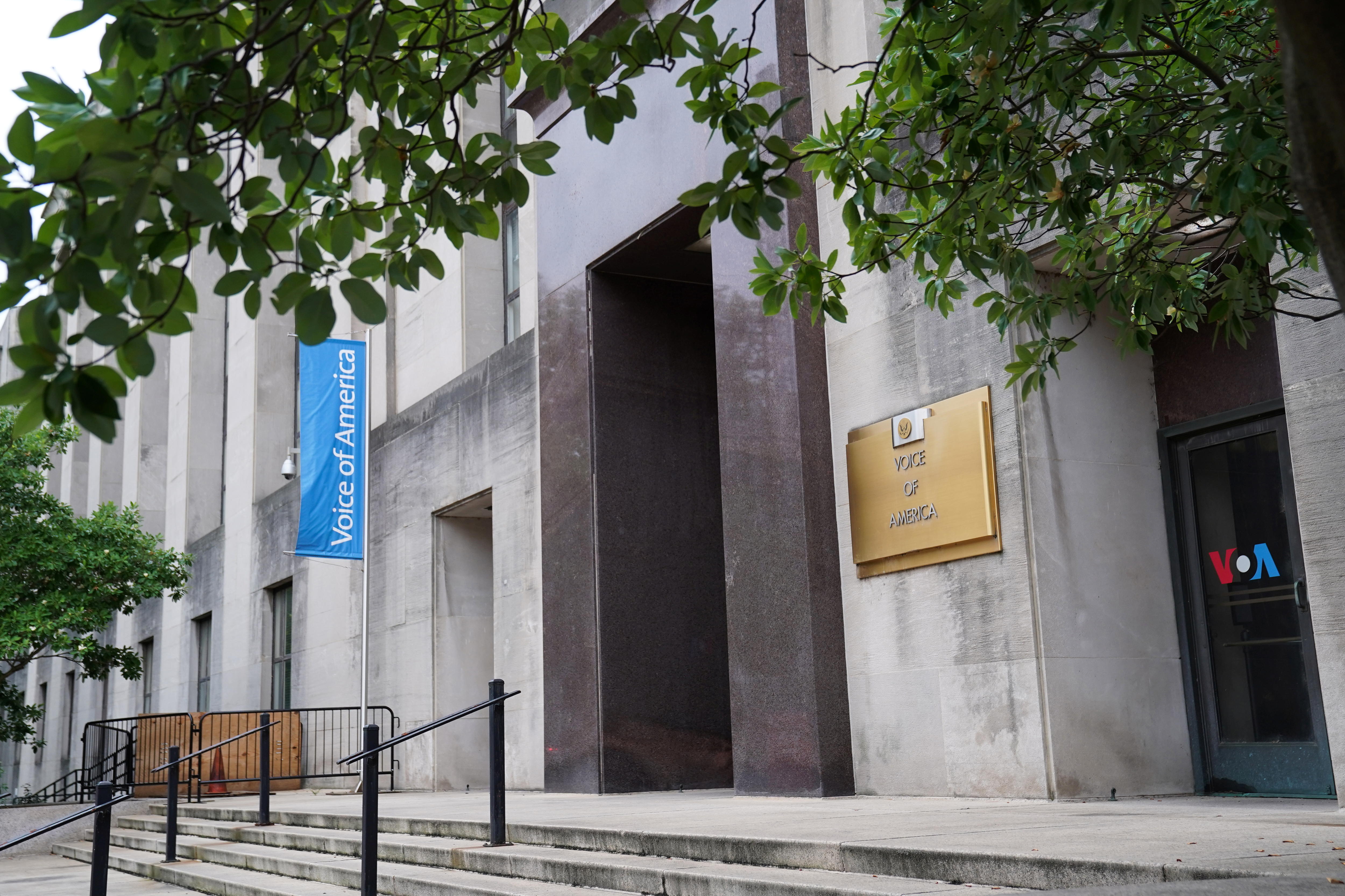 The exterior of a building from the street with a sign hanging off the front.