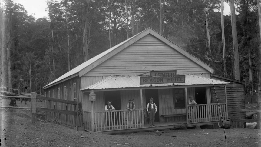 Black and white photograph of men standing on verandah of timber building with sign above for Beacon Hotel, c 1898.
