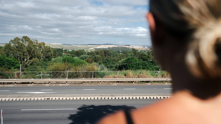 over the shoulder view of a young woman looking at a coal mine in the distance