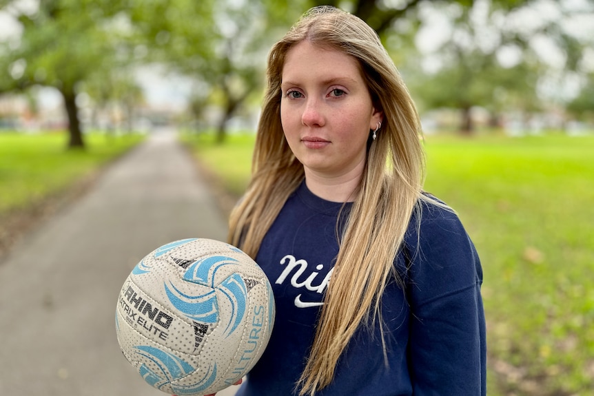 Mackenzie holding a netball with a serious look on her face. 