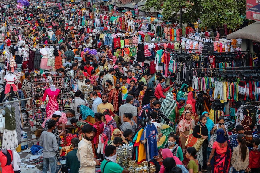 A huge crowd of people in a brightly coloured, outdoor marketplace