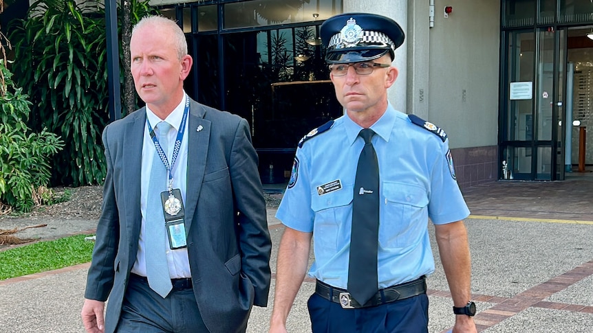 Two men, one in a suit, the other in police uniform, walking together