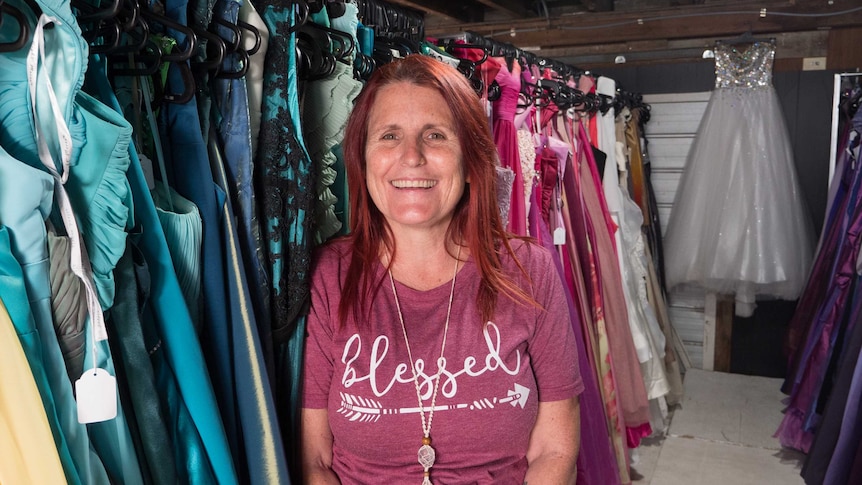 Tammy standing in front of the donated formal gowns