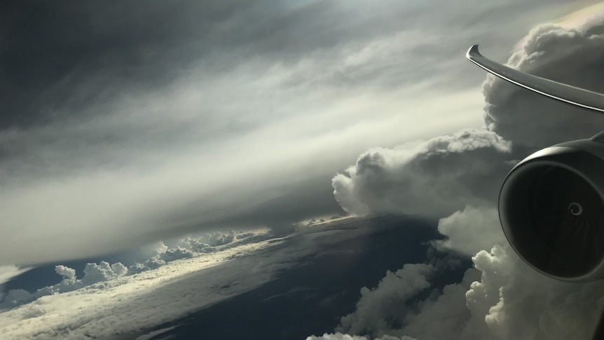 Clouds in the sky and a plane engine, seen from an airline passenger seat window.