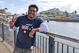 Sri Lankan seafarer Bandara Ranaseha wears an Australian flag t-shirt while standing in front of Townsville city.