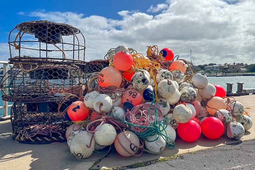 Three lobster pots stacked up sit beside a pile of buoys.