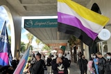 People holding LGBTQIA+ flags and gathering in St Kilda. 