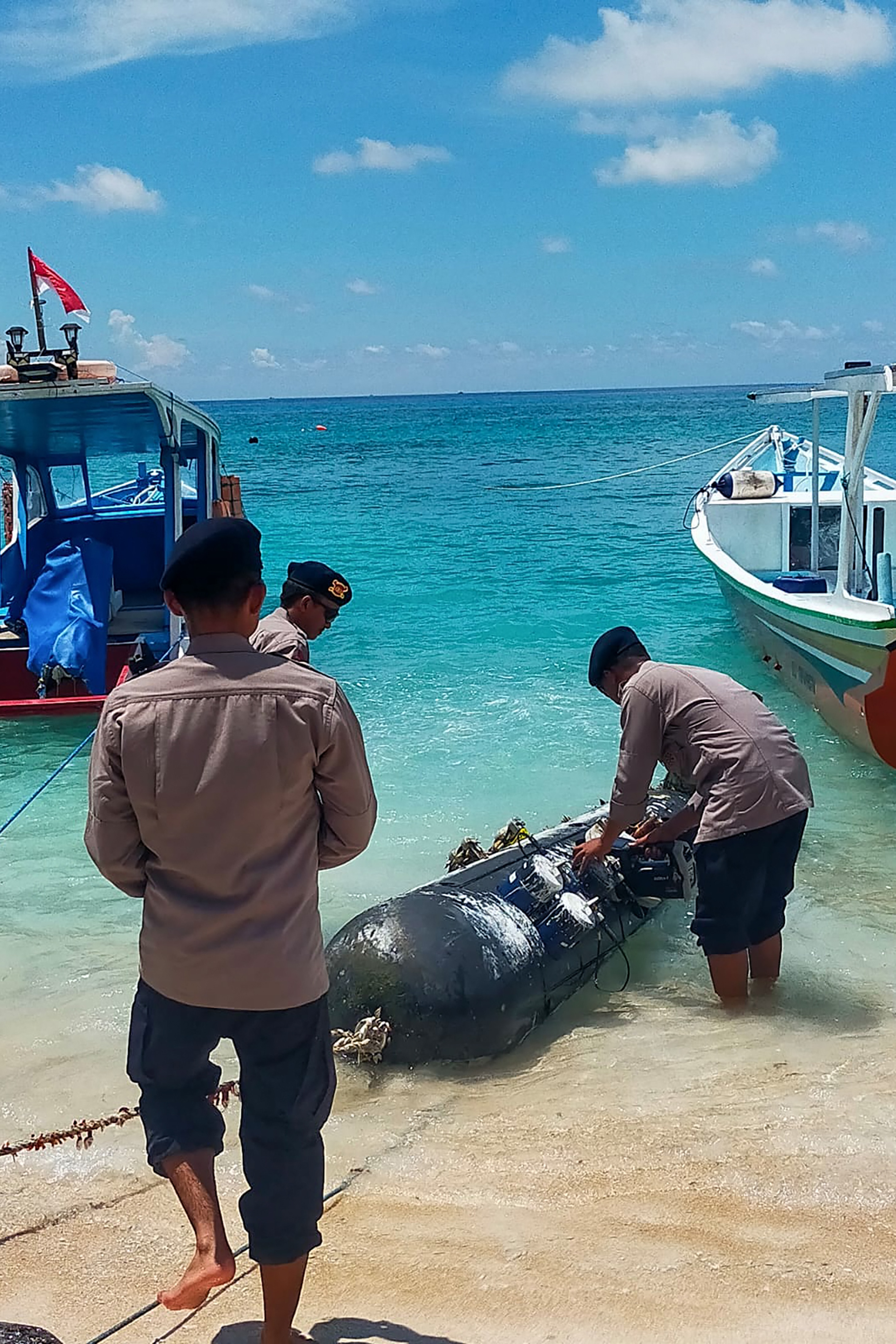 Indonesia navy personnel bring a torpedo-like device ashore.