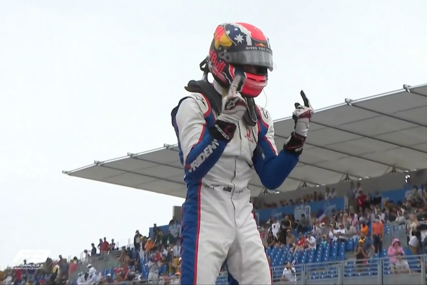 Racing driver celebrates win on top of his car.
