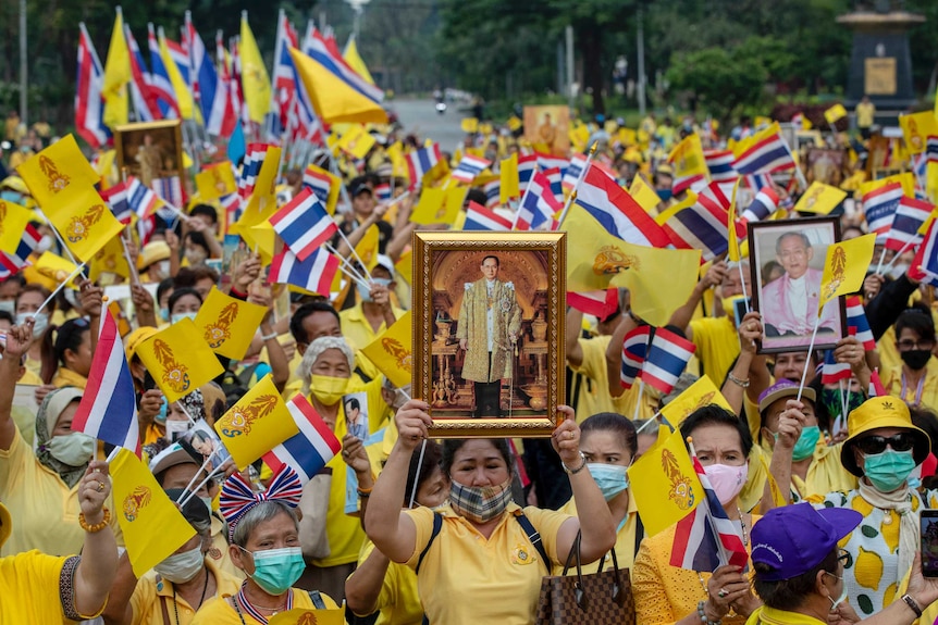 Les partisans de la monarchie thaïlandaise, vêtus de jaune, affichent des images du défunt roi Bhumibol Adulyadej lors d'un rassemblement.