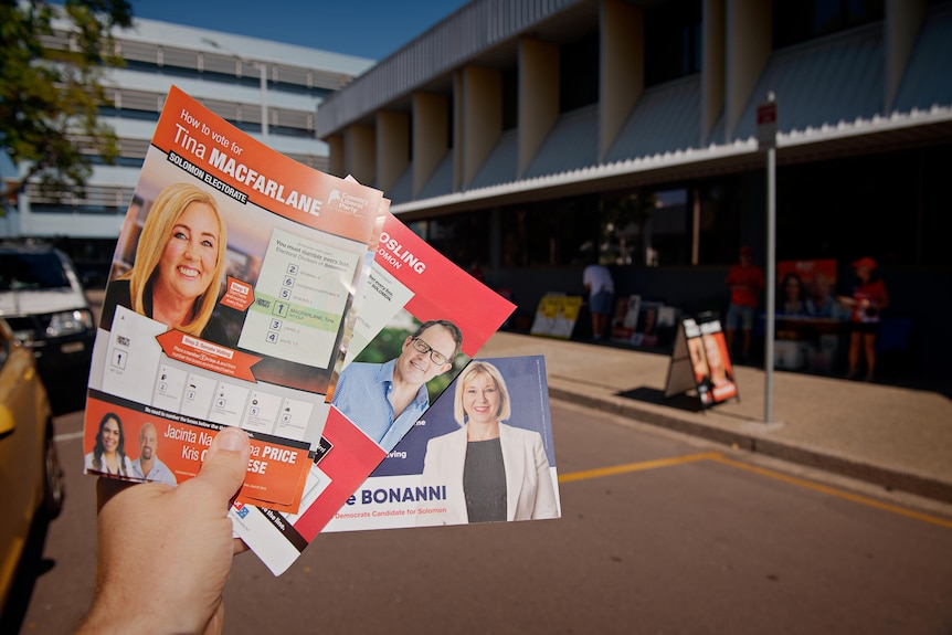 A hand holds a series of how to vote election cards.