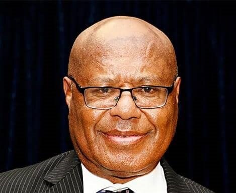 Headshot of a bald black man wearing glasses, suit and tie