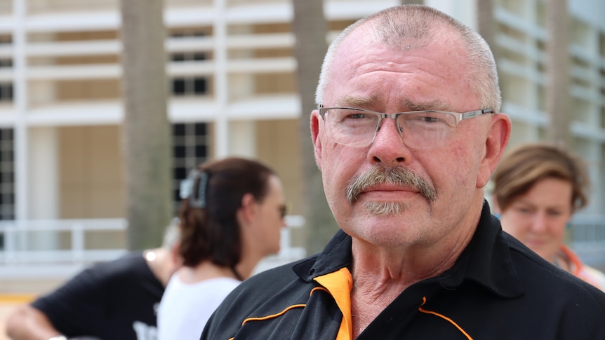 A man wearing glasses and a polo shirt looks at the camera. 