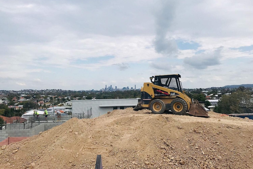 Excavator at housing construction site at Wavell Heights with Brisbane CBD in background.