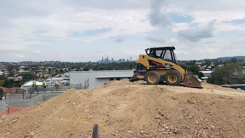 Excavator at housing construction site at Wavell Heights with Brisbane CBD in background.