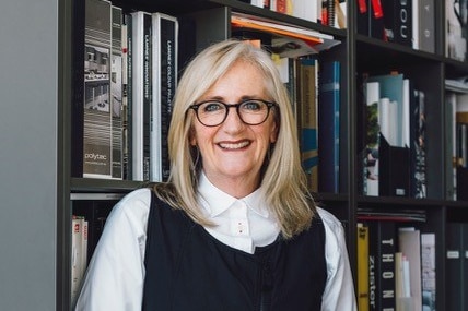 Fiona Austin smiles as she stands in front of a bookcase.