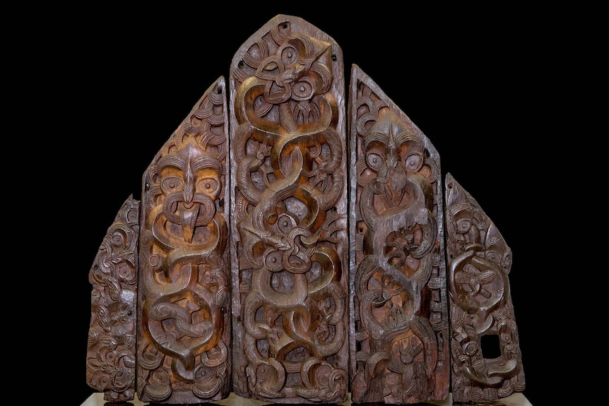 Five wooden panels intricately carved with serpentine figures.