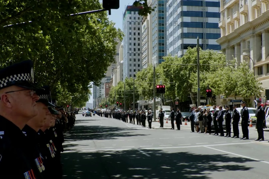 Hundreds of people, mostly officers, line the streets in a guard of honour 