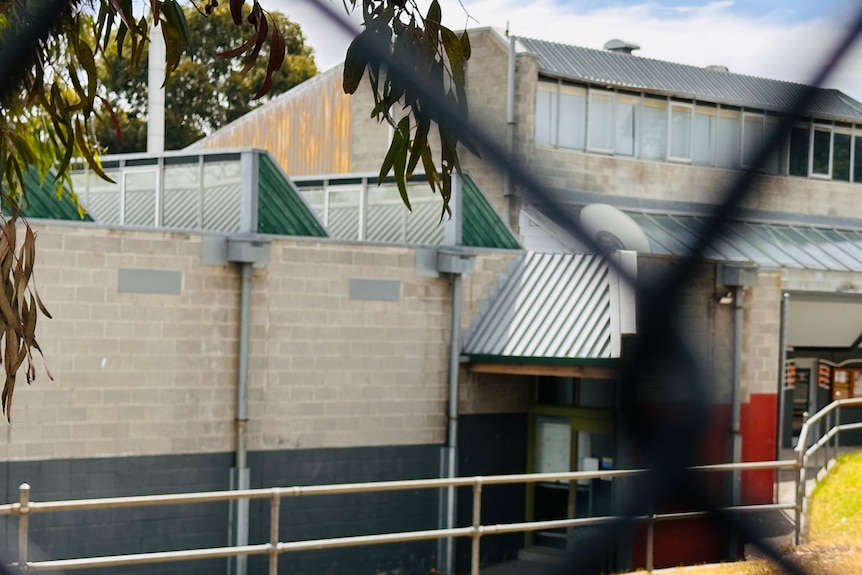 A school building is seen through a chain link fence.