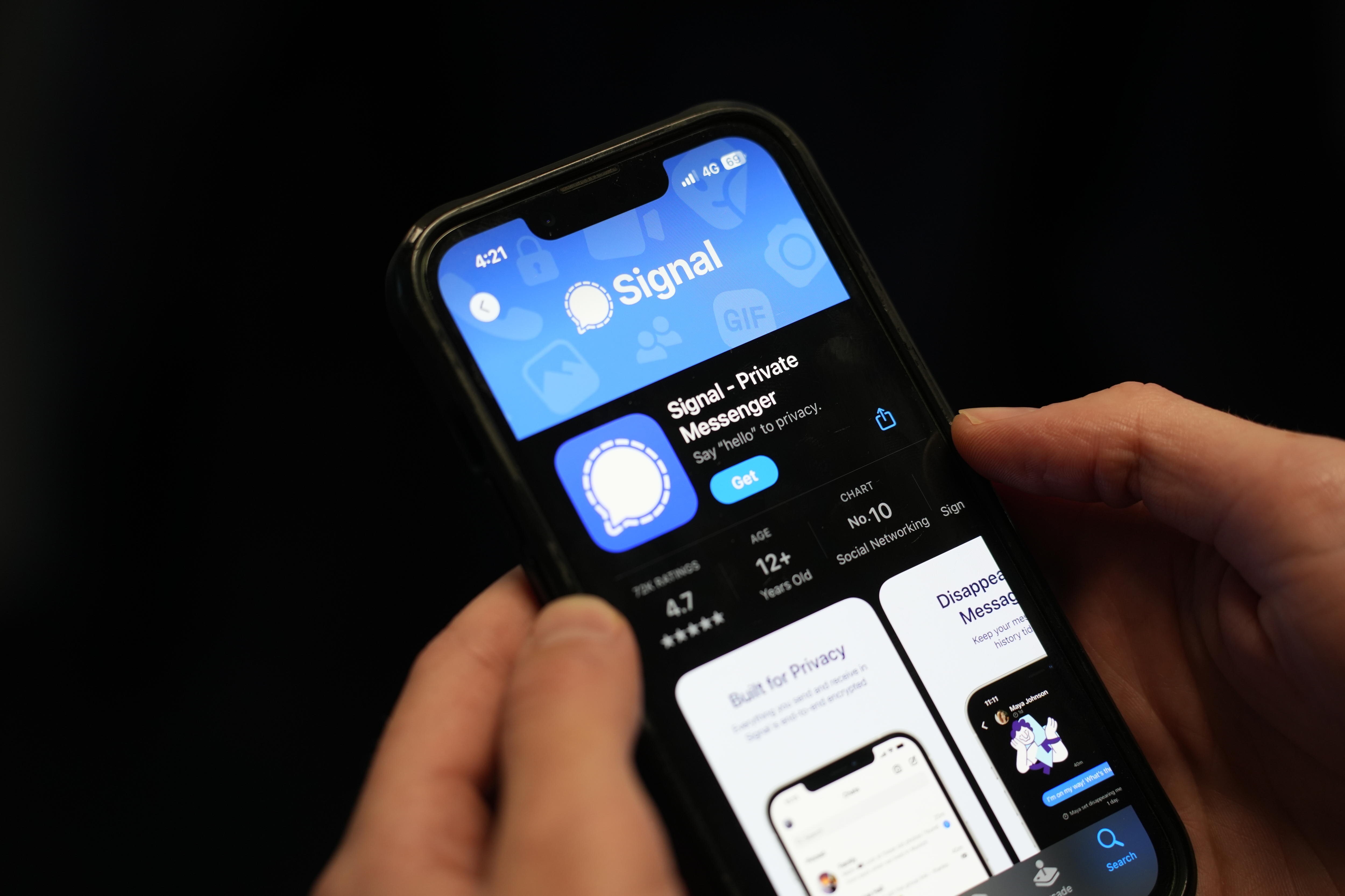 Hands hold a smartphone showing the Signal app logo