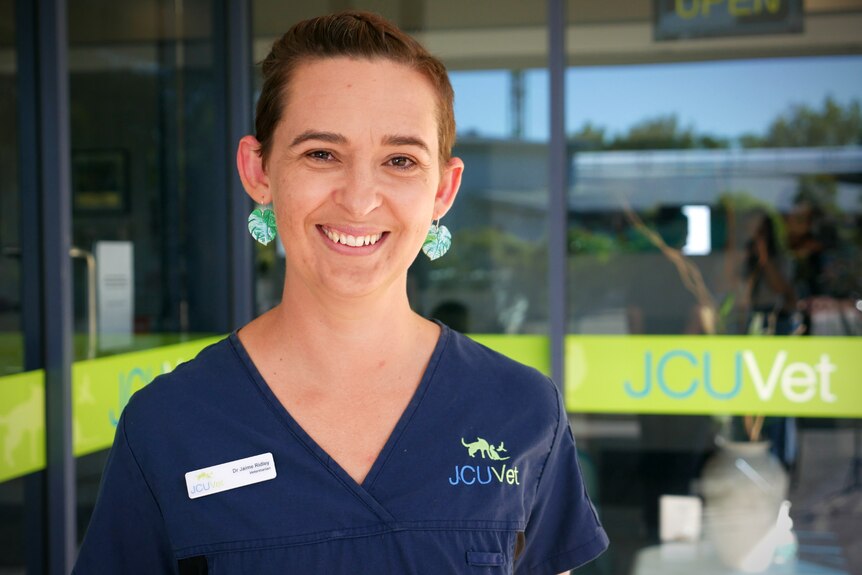 Dr Jaime Ridley in a pair of scrubs stands in front of the JCU vet clinic