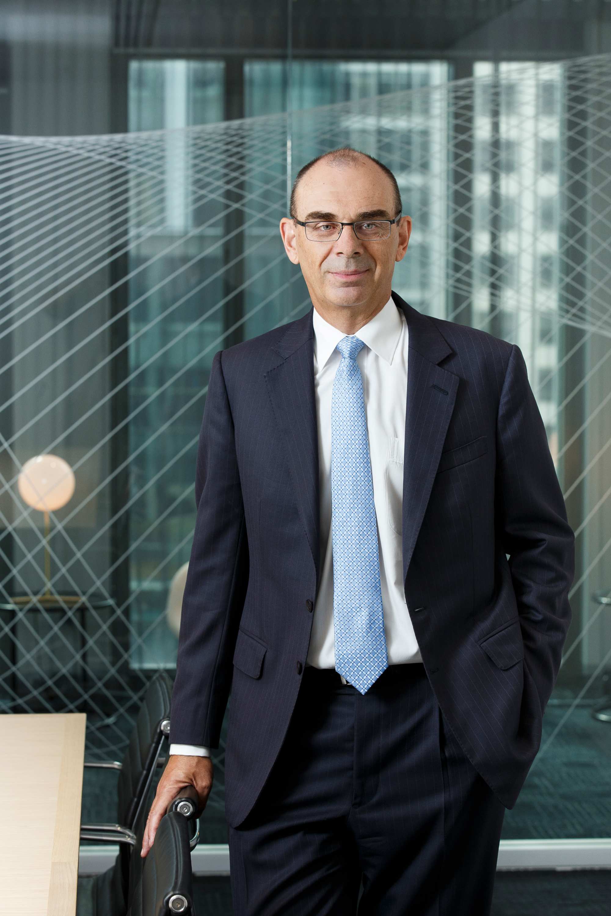 Photo of APRA chairman Wayne Byers standing in a boardroom.