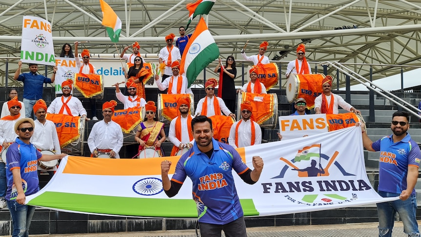 A group of Team India fans hold the Indian flag and banners