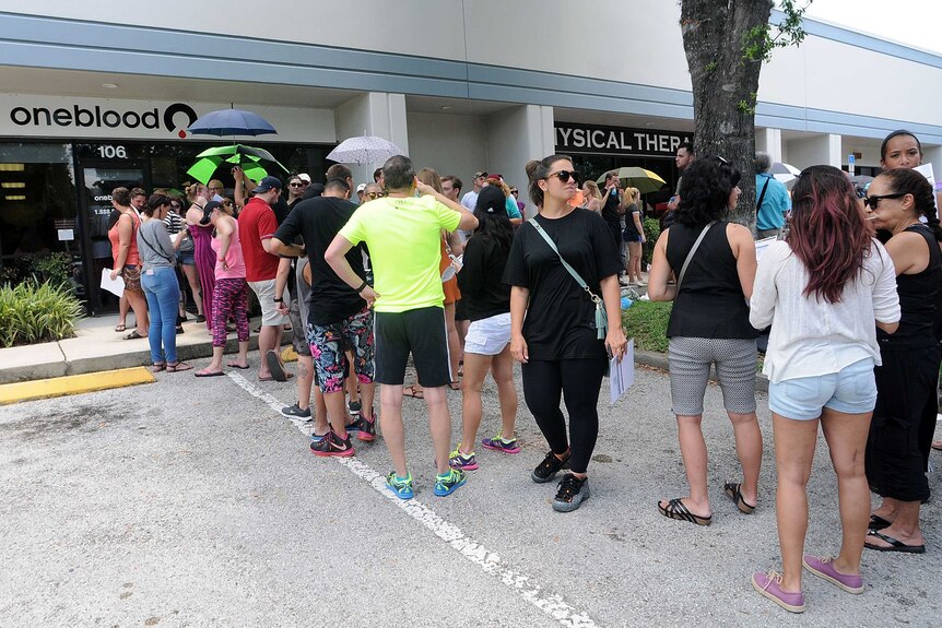 A line of people queue outside a blood donation centre.