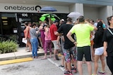 A line of people queue outside a blood donation centre.