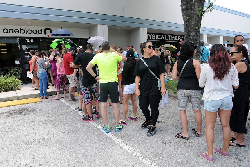 A line of people queue outside a blood donation centre.