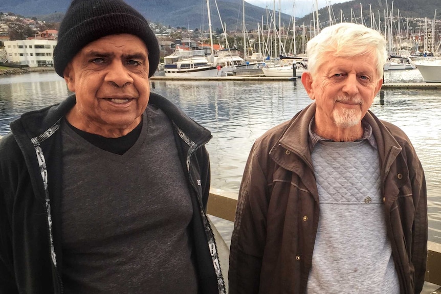 Three people stand side by side near a marina