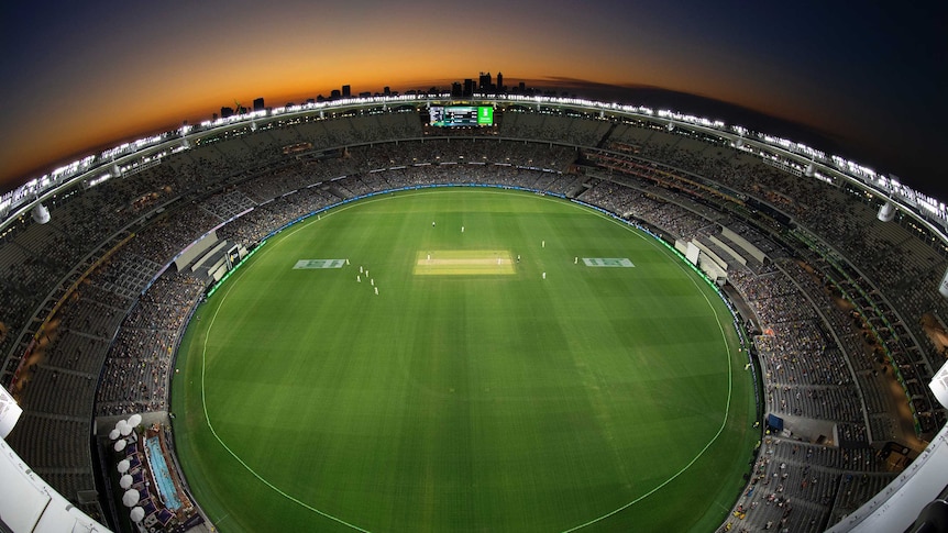 Perth stadium with lights on as the sun sets behind it