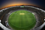 Perth stadium with lights on as the sun sets behind it
