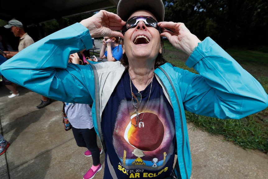 Woman reacts as she puts her glasses on during an eclipse watch party in Des Moines, Iowa