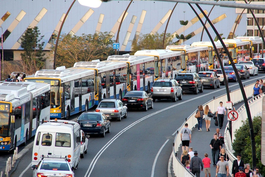 A row of buses on a bridge.