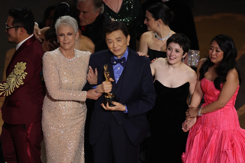 Jamie Lee Curtis, James Hong and others stand on stage as Everything Everywhere All at Once accepts the Oscar for best picture.