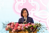 Taiwan's President Tsai Ing-wen standing at a lectern adorned with flowers