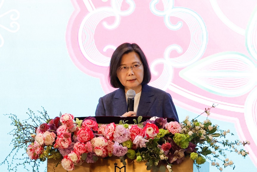 Taiwan's President Tsai Ing-wen standing at a lectern adorned with flowers