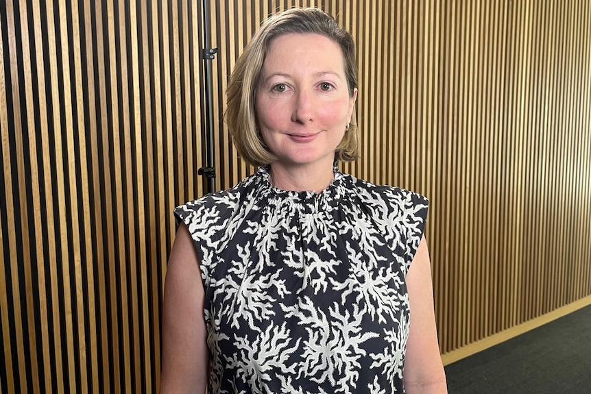 Katherine Hayes standing in front of a wooden wall. 