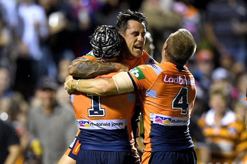Mitchell Pearce of the Newcastle Knights embraces teammates after scoring try