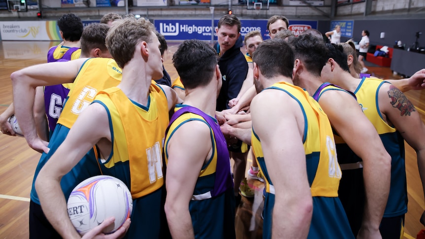 Members of the Australian Opens Mens Netball put their hands in the circle together during a practice session