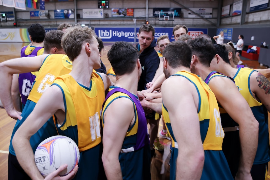 Members of the Australian Opens Mens Netball put their hands in the circle together during a practice session