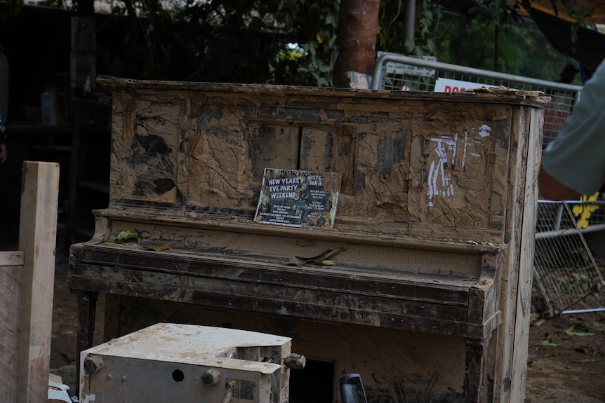 Piano caked in brown mud, with sheet music still sitting on the lid.