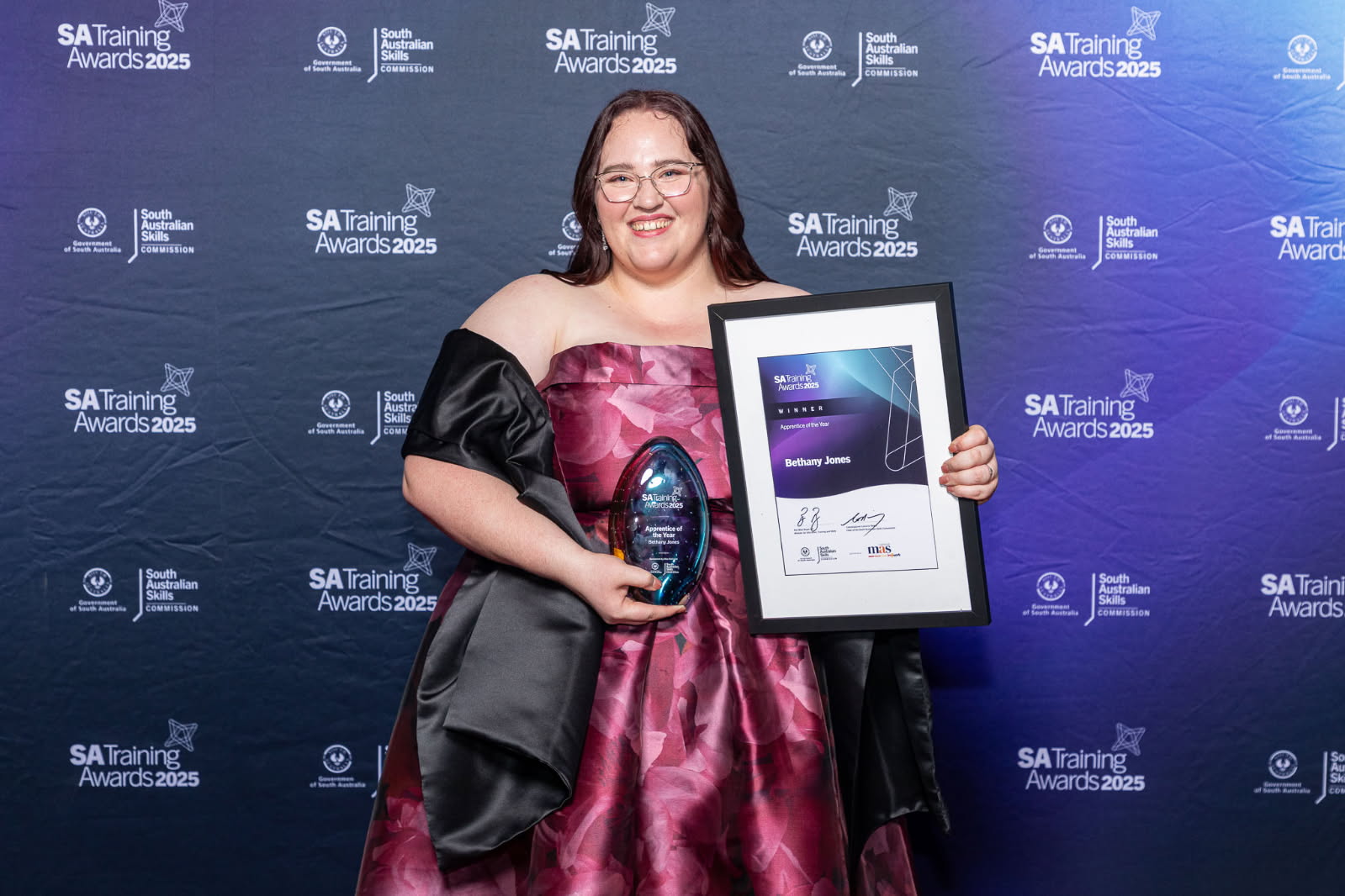 Beth en un discurso formal con trofeo y certificado.