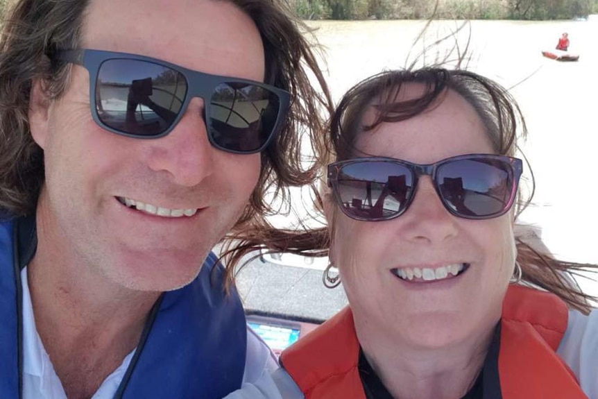 A selfie of a smiling couple on a boat on the River Murray towing a young rider.